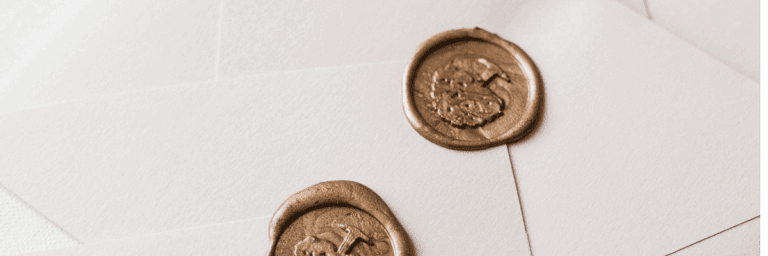 Elegant invitations with cream envelopes and ornate gold wax seals on white background