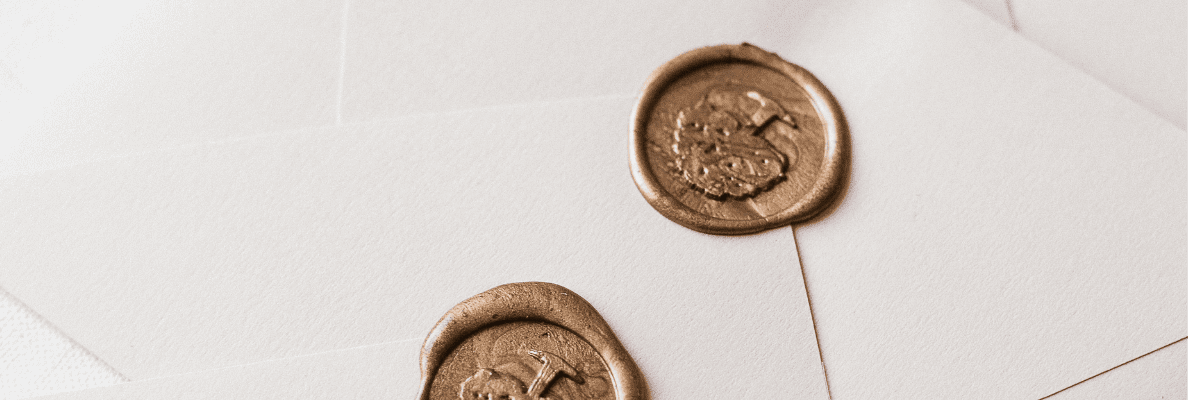 Elegant invitations with cream envelopes and ornate gold wax seals on white background