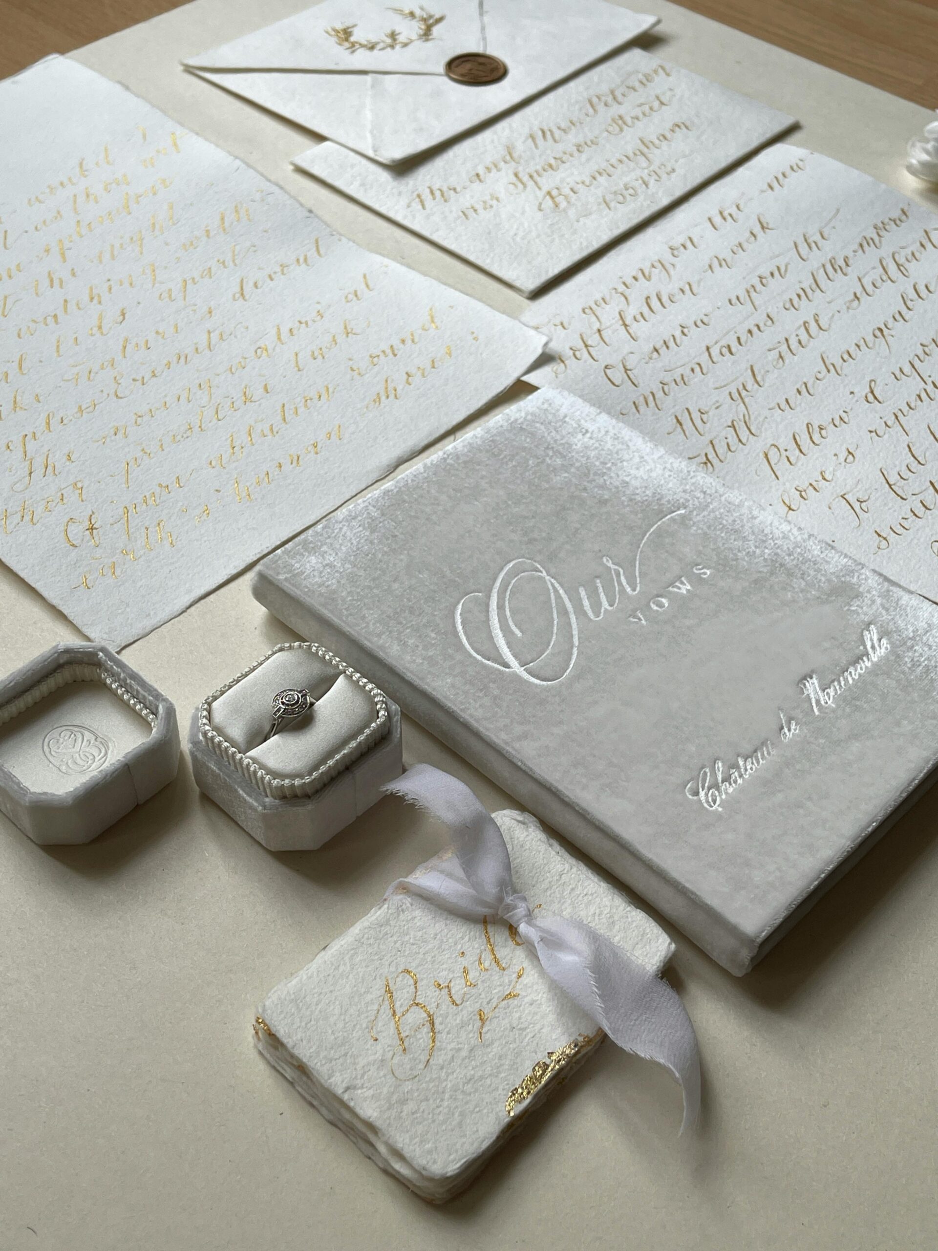 Luxury wedding stationery set with gold calligraphy invitations, ring box and bride label on velvet notebook