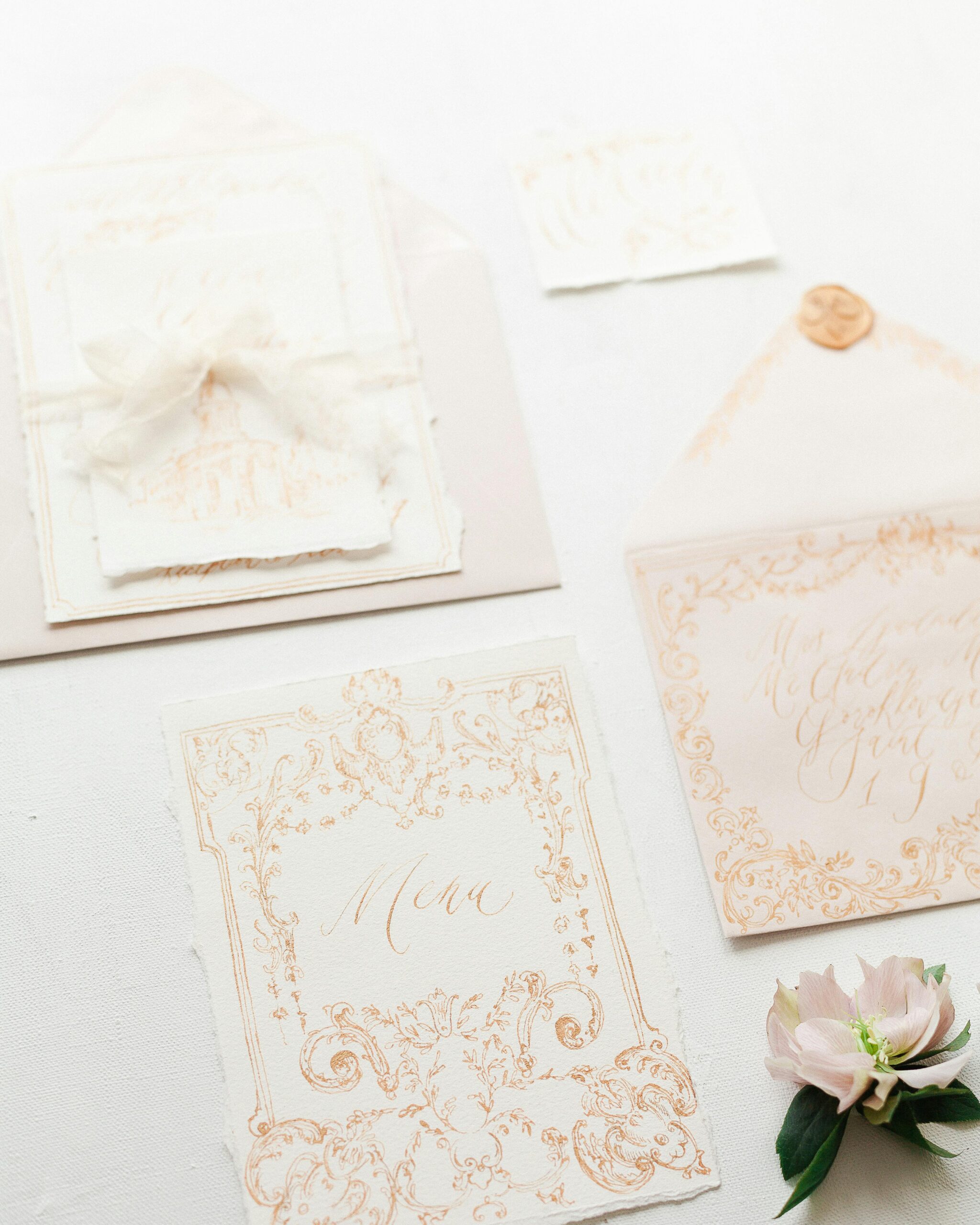 Elegant invitations with Rococo stationery, cream envelopes, silk ribbon, and gold wax seal.