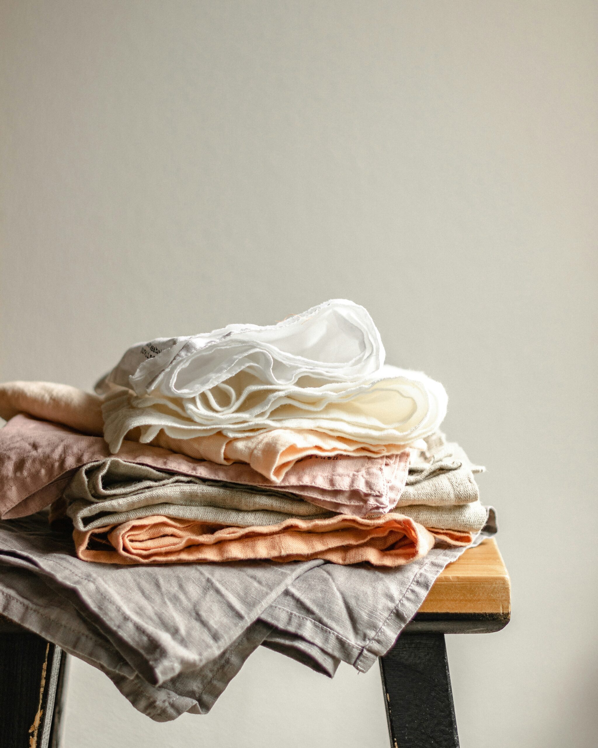 Linen fabric luxury table linens in white, peach, taupe, and blush stacked naturally.