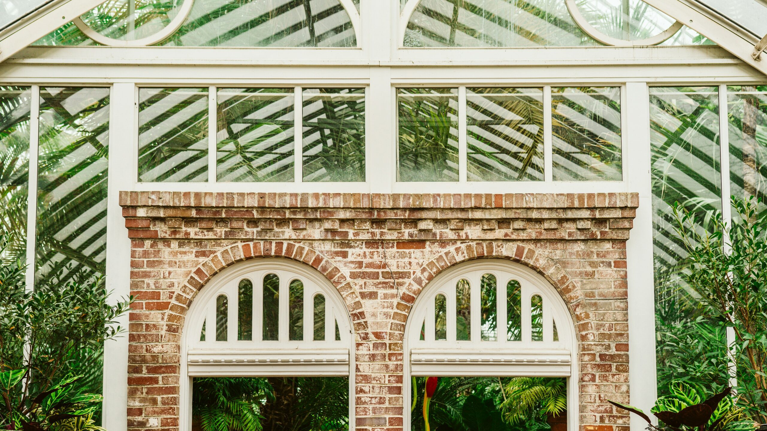 Victorian orangery winter garden with twin arched brick windows and slender iron glazing bars