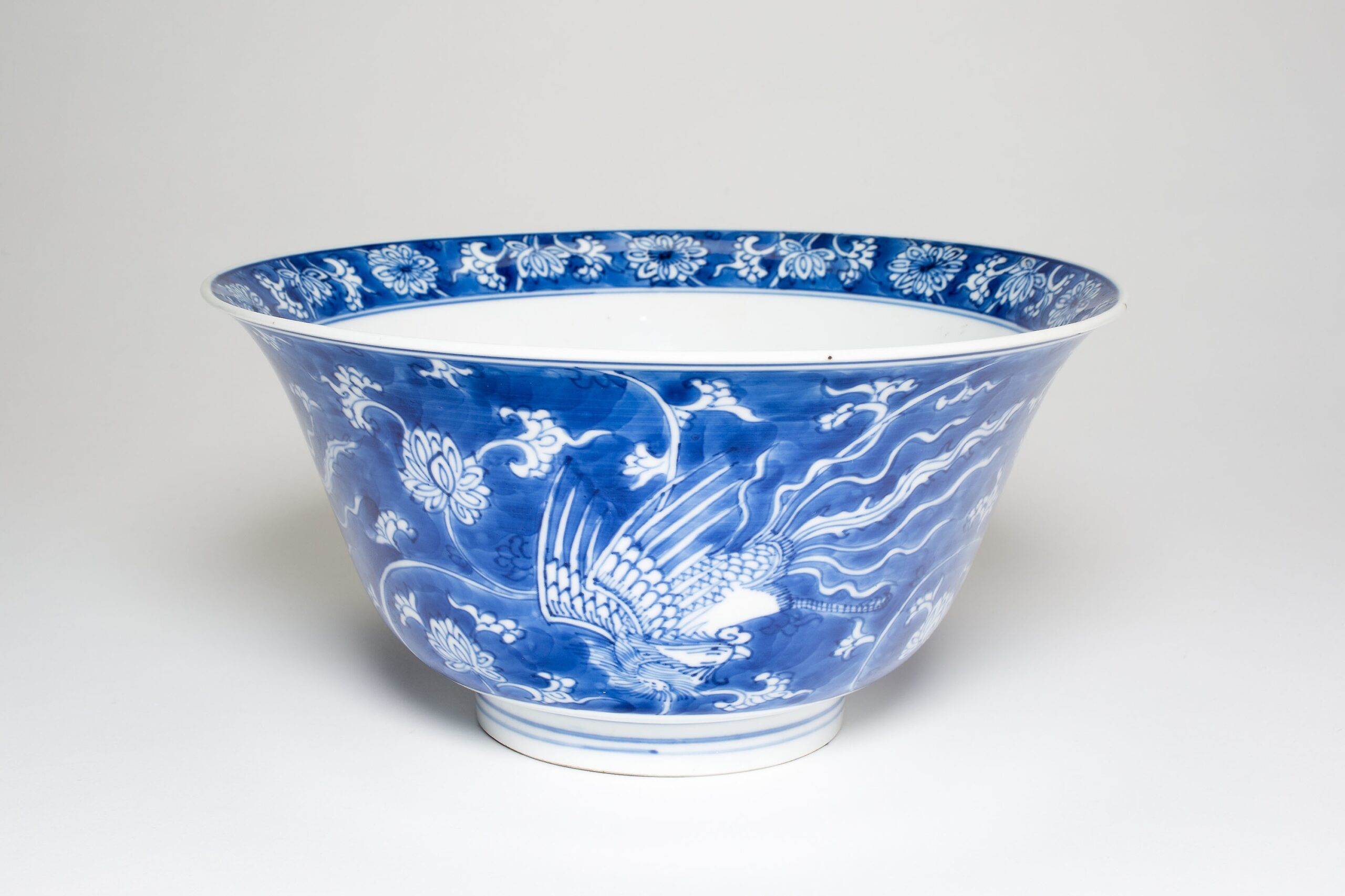 Cobalt blue porcelain bowl with underglaze phoenix in flight amid traditional Chinese clouds